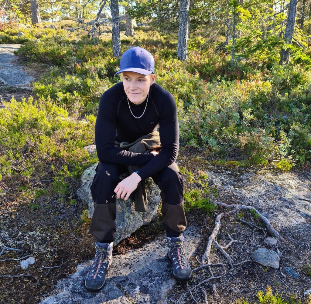 Johan sitter på sten i skogen