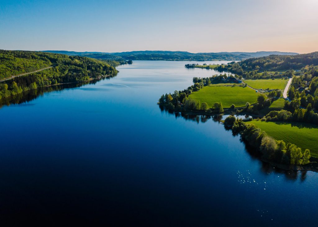 Blå sjö omringad av grön natur